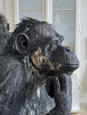 Skulptur Gorilla, der nachdenklich schaut und das Kinn auf eine Hand stützt.